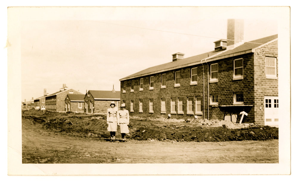 Black & white photos of two WWII WAACs standing in front of brick barracks.  New construction in 